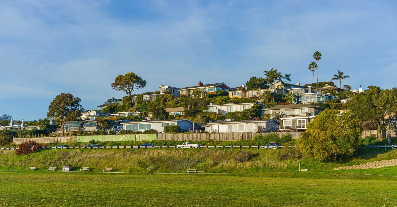 A hillside neighborhood of California homes above an open green field