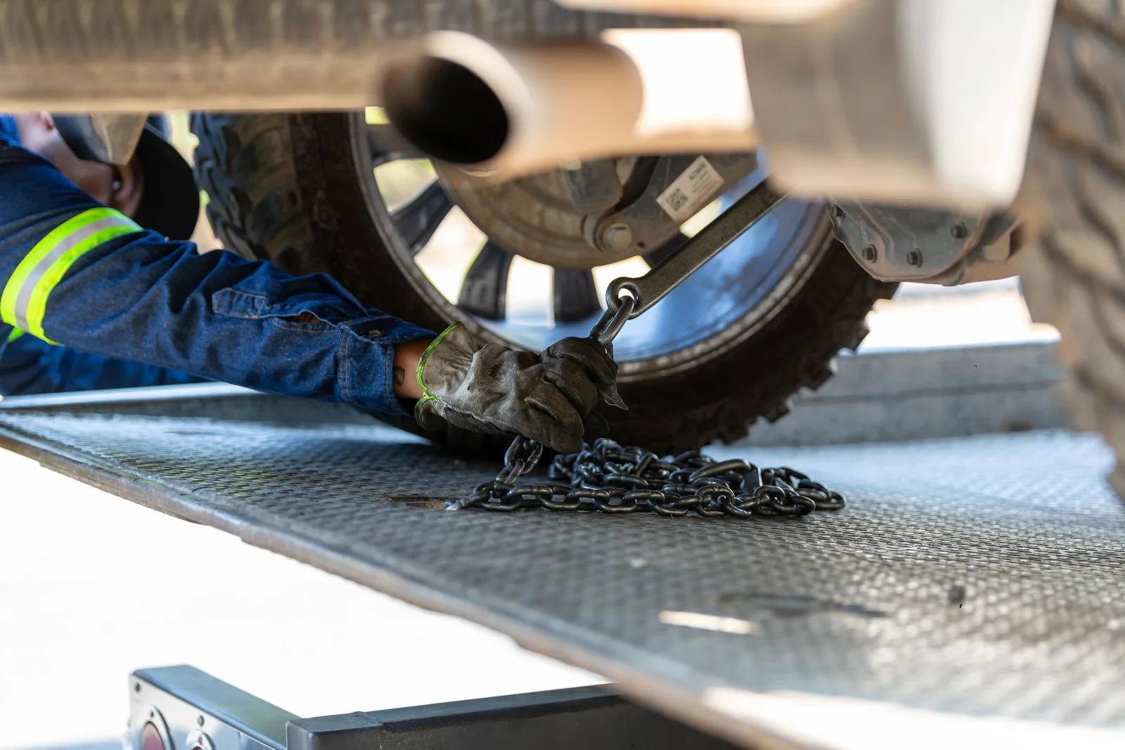 Tow operator securing a vehicle to a flatbed with a chain