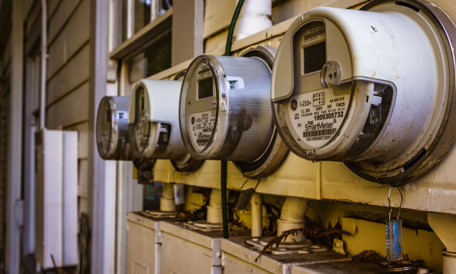 A row of smart electricity meters mounted on the exterior wall of a residential building