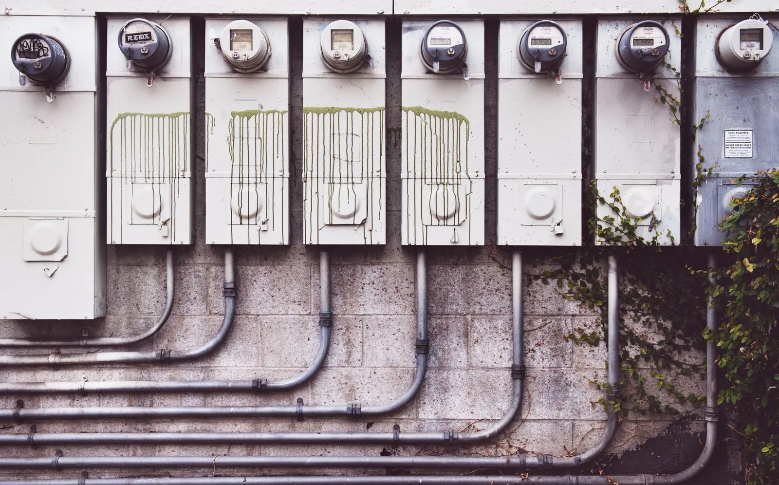 A row of outdoor residential electric meters mounted on a brick wall