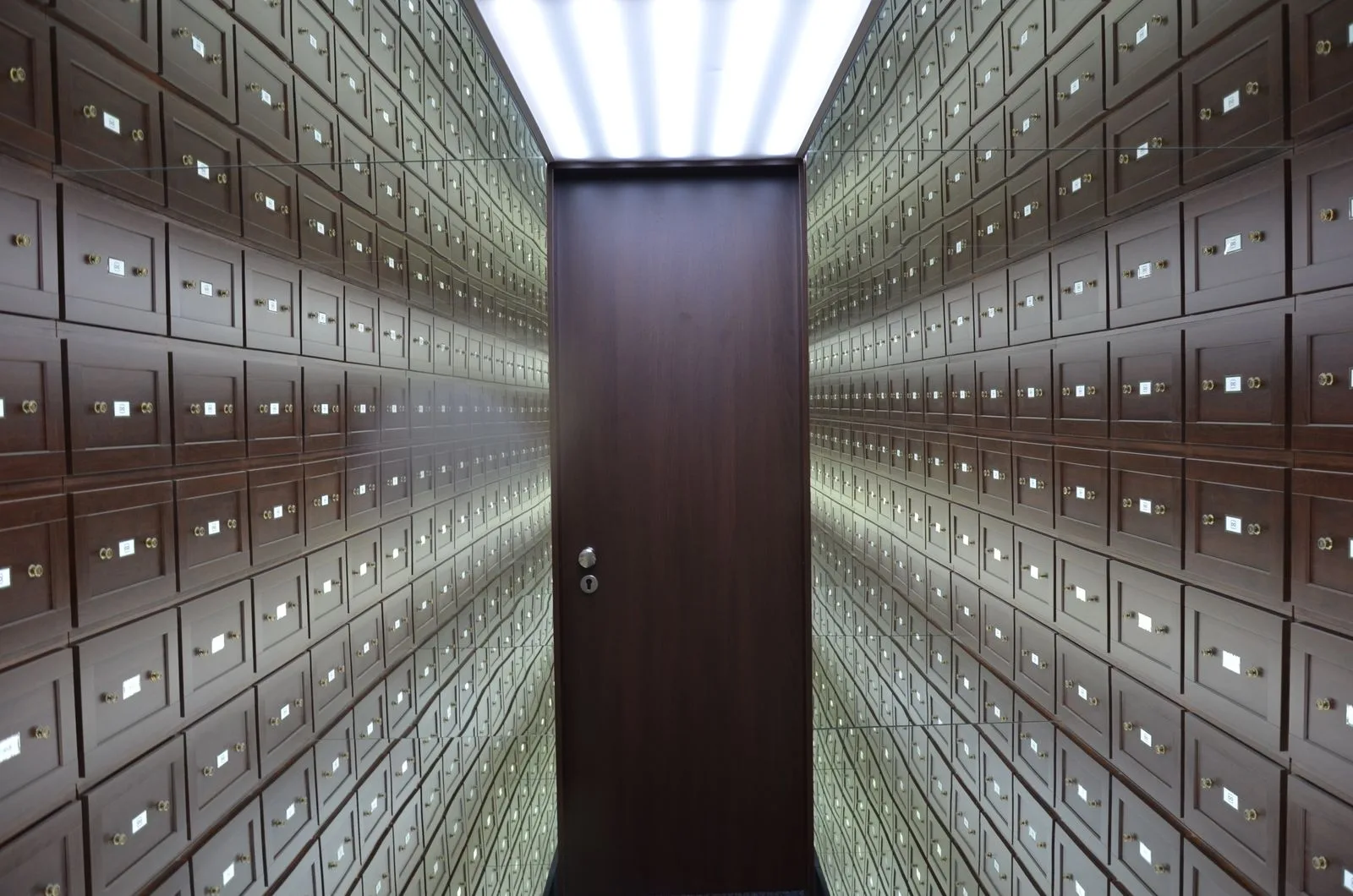 Rows of wooden safe deposit boxes lining both walls of a bank vault room
