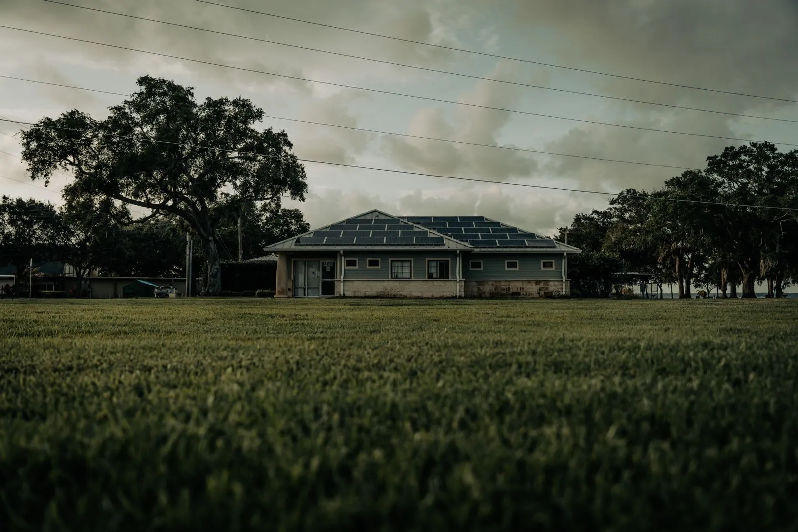 Single story Florida home with rooftop solar panels under a heavy evening sky
