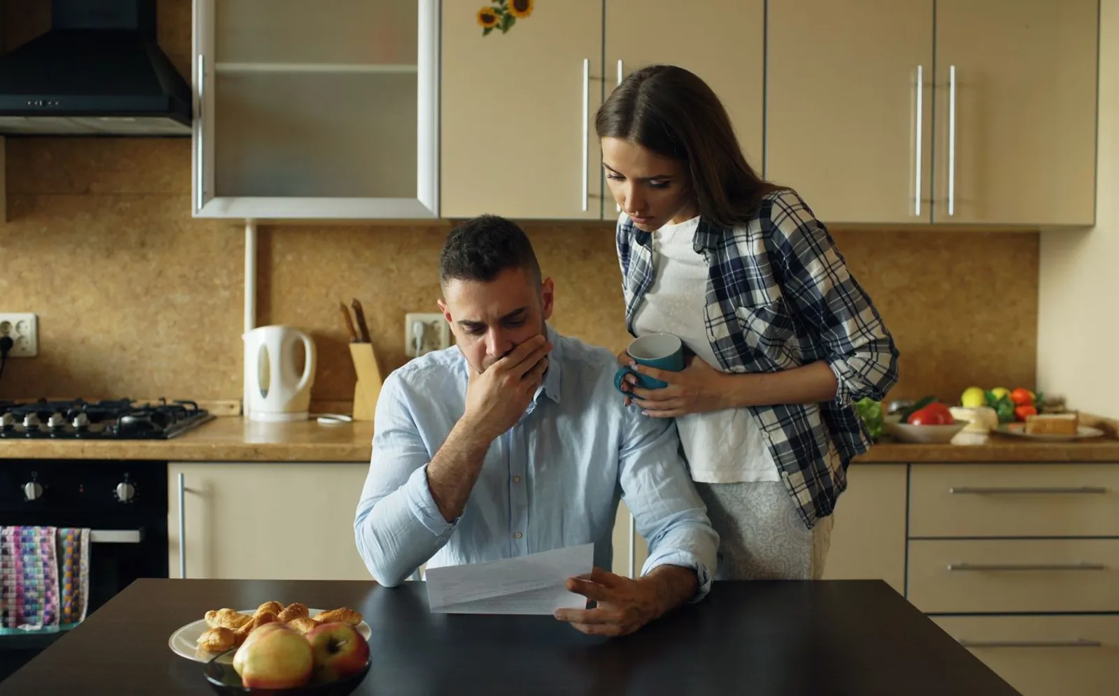 A couple reading a financial document at their kitchen counter