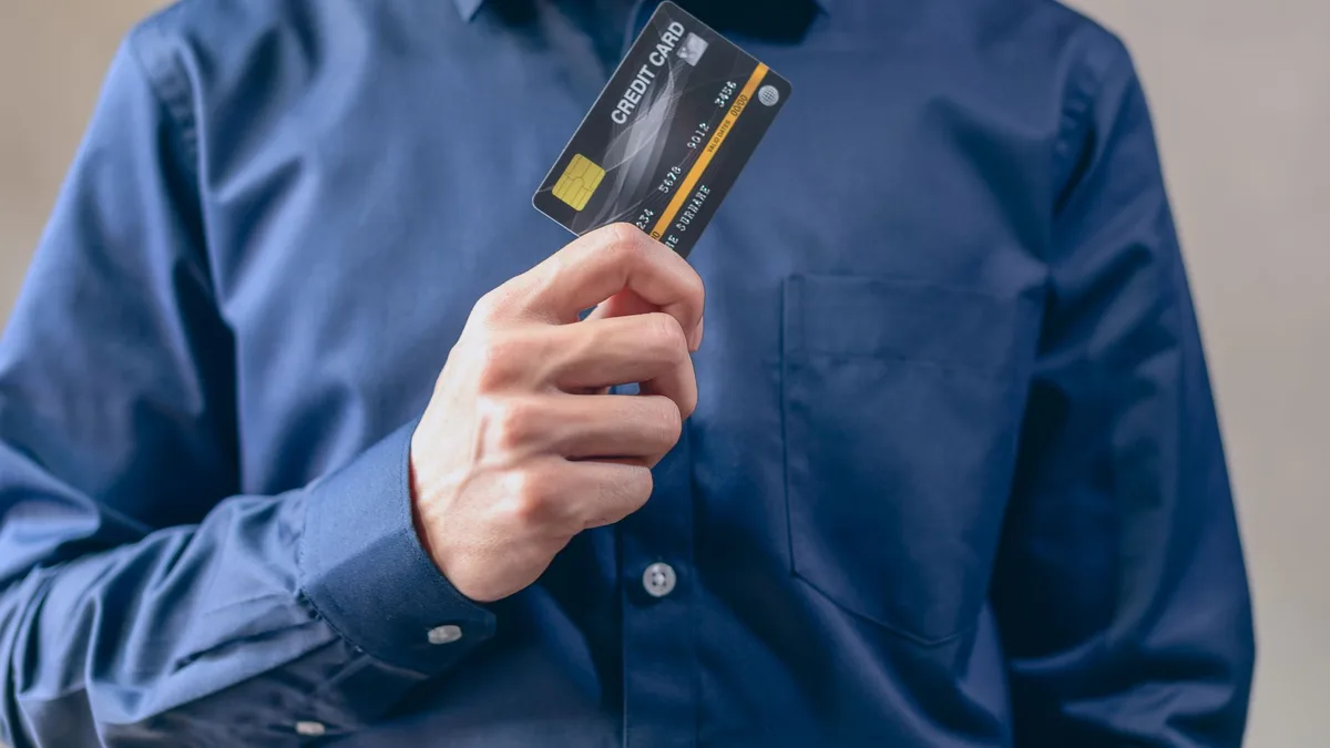 Close-up of a man in a blue shirt holding a credit card