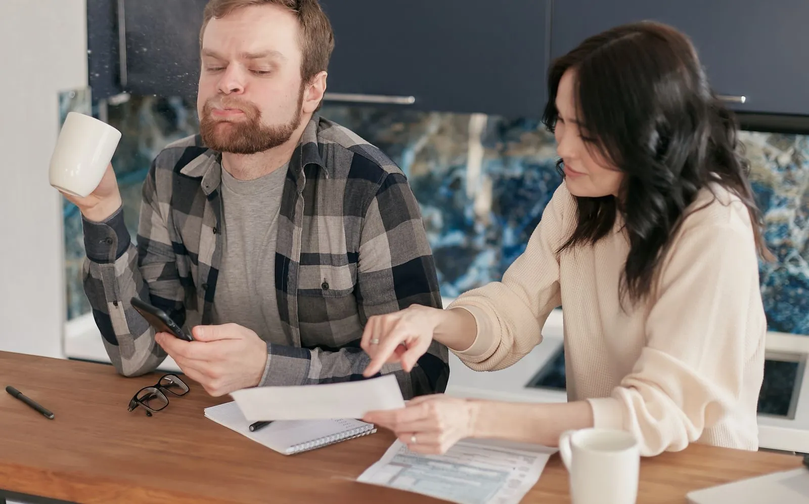A couple reviewing bills and paperwork at a kitchen table