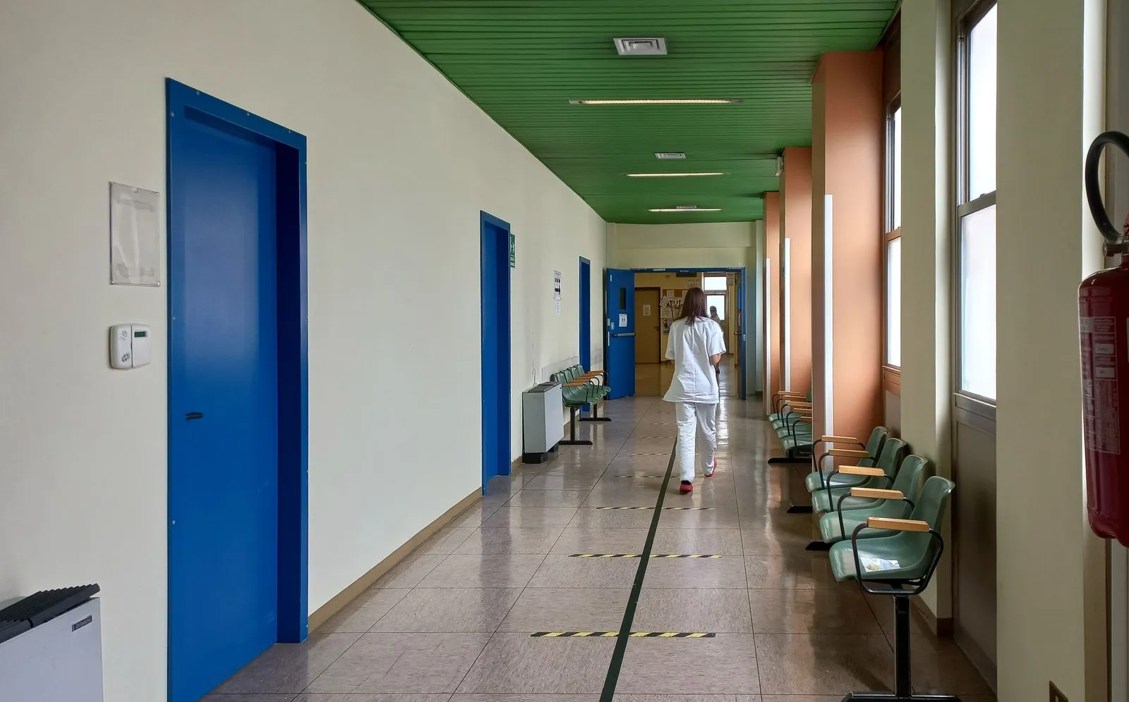 A healthcare worker walking down an empty hospital corridor