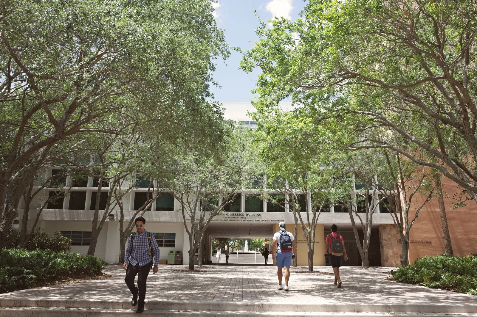 Students walking through a sunlit university campus on a bright day