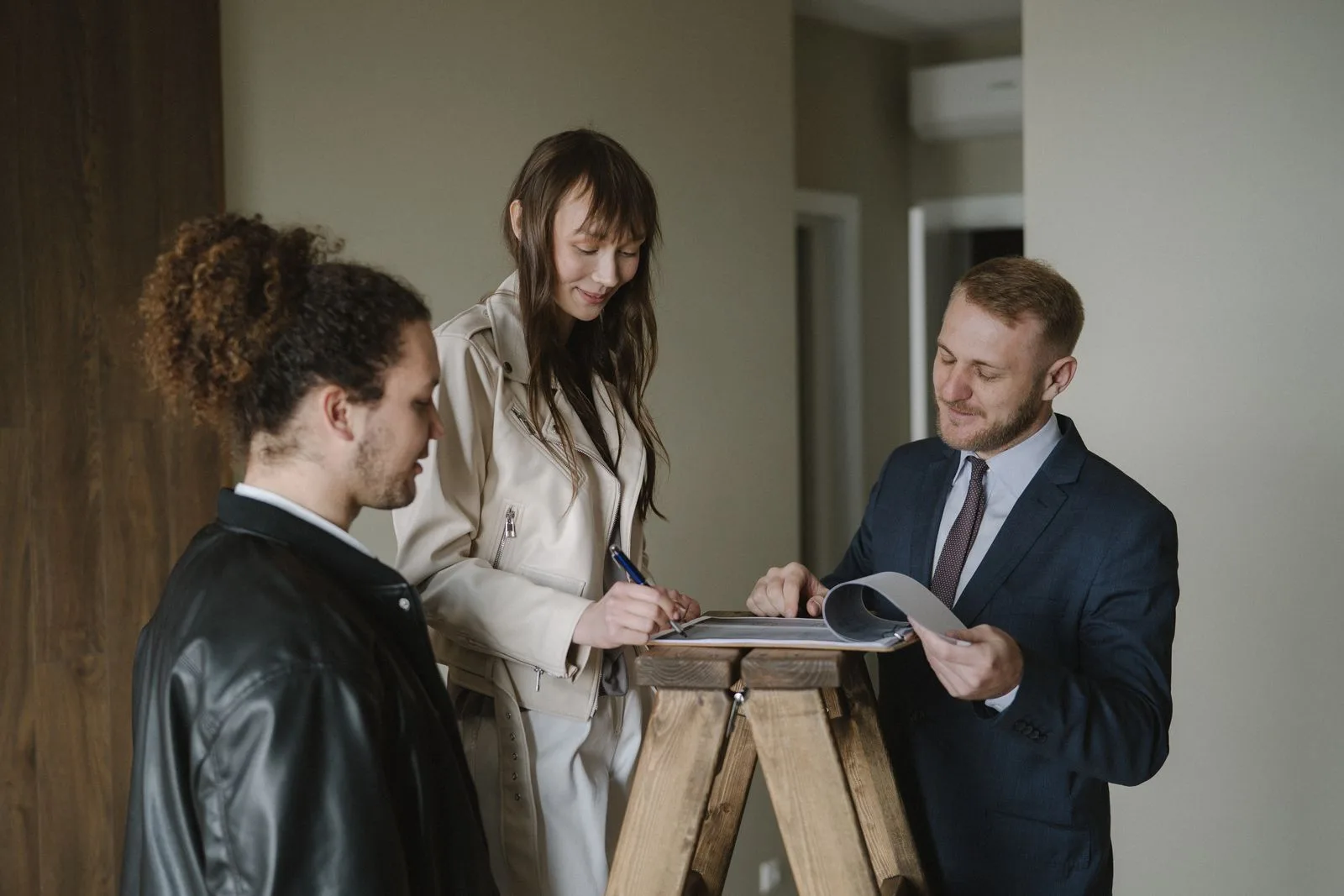 A couple signing home purchase paperwork with an agent in an empty room