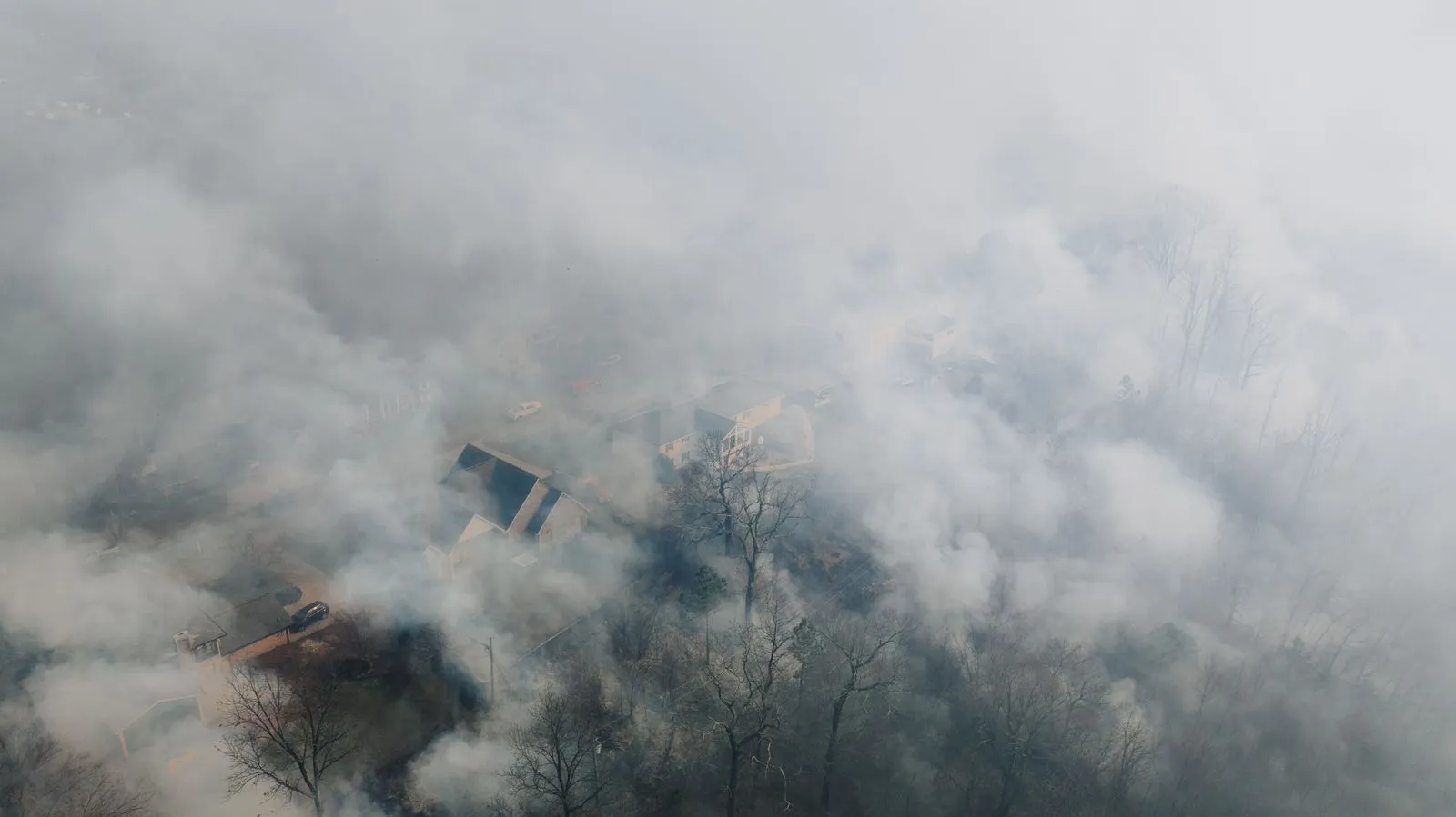 Aerial view of a neighborhood of houses shrouded in thick wildfire smoke