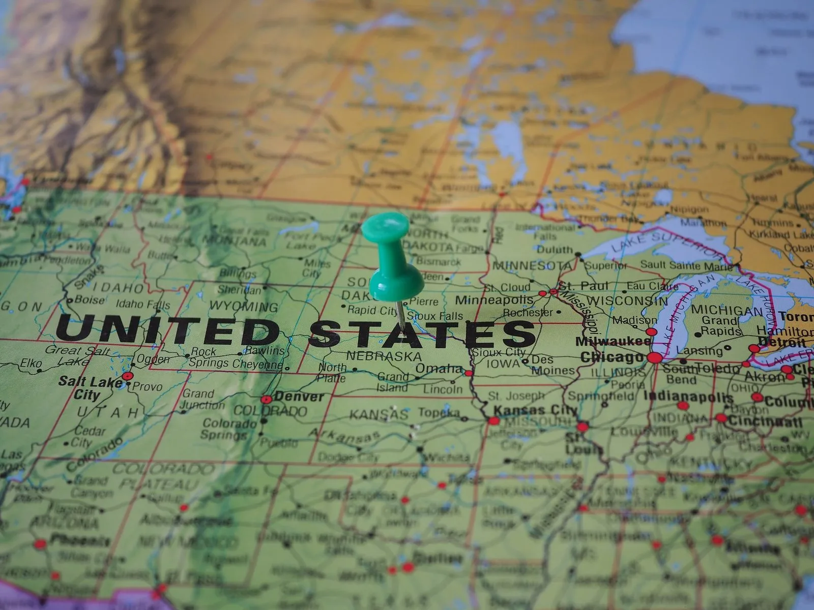 A green pin stuck into a printed road map of the United States