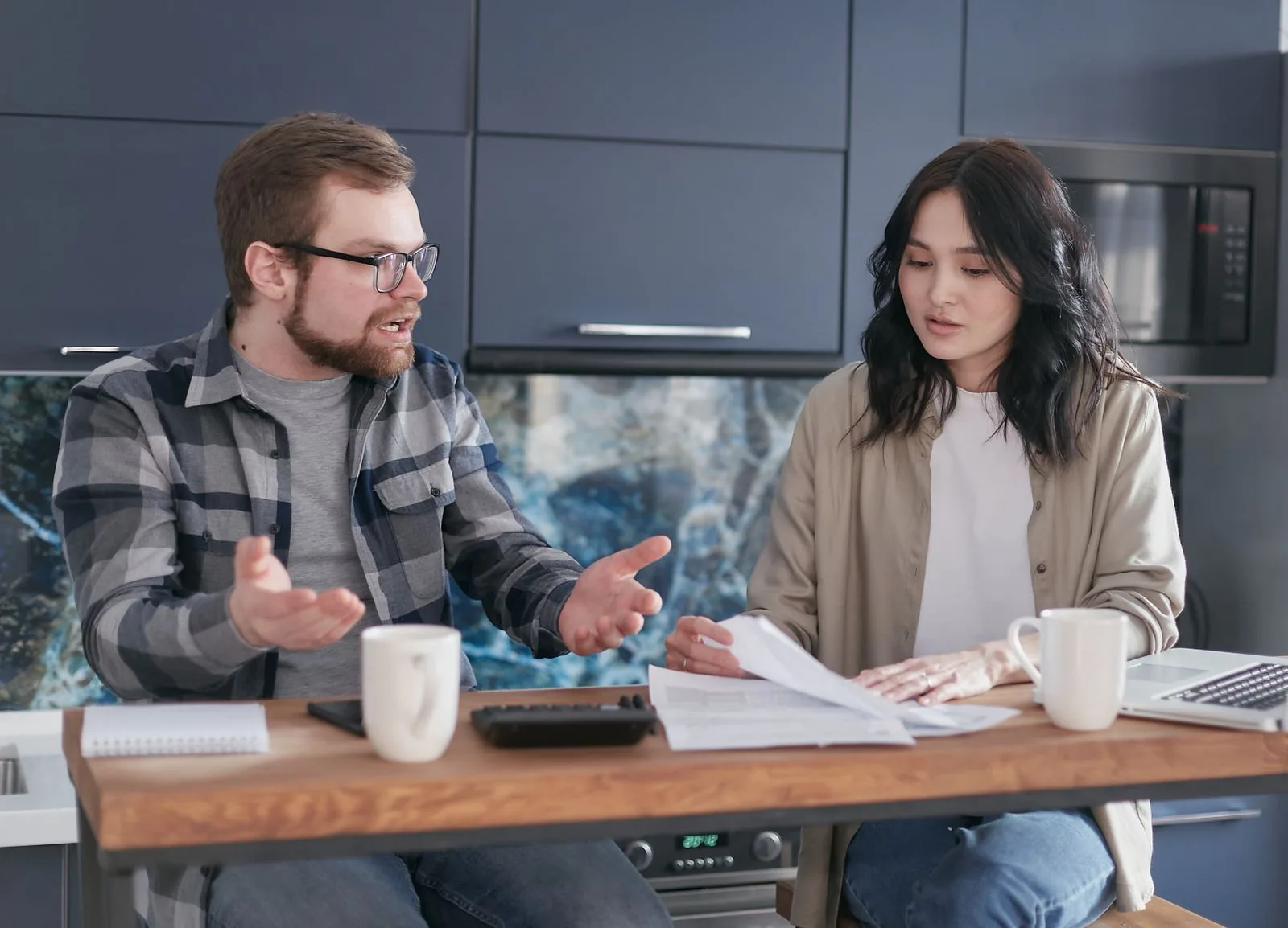 A couple at a kitchen counter going through bills and paperwork together